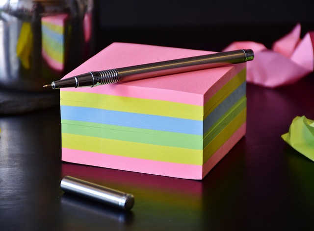 Długopis reklamowy leży na kolorowych biurowych karteczkach